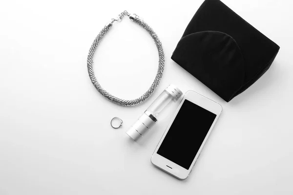 Bouteille de parfum, smartphone et collier sur fond blanc — Photo