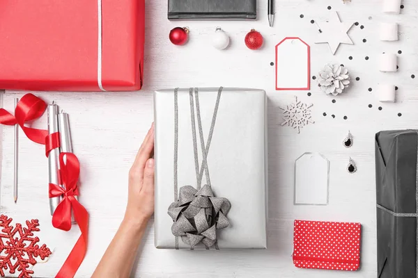 Vrouw met geschenkdozen en kerstversiering aan tafel — Stockfoto