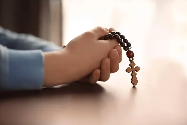 Niño sosteniendo la cruz de madera en la mesa — Foto de Stock