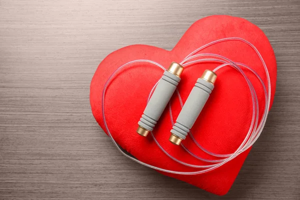 Jumping rope and red heart on wooden background. Cardio training concept — Stock Photo, Image