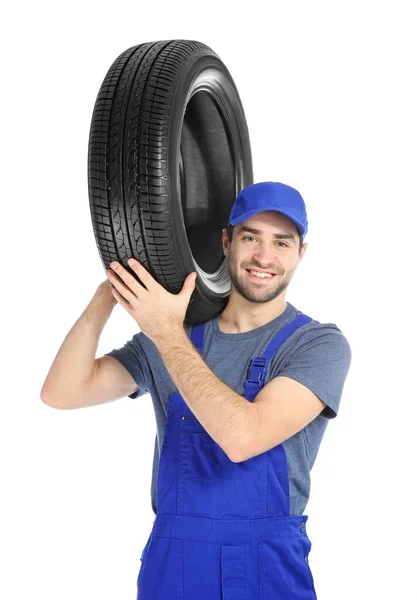 Jeune mécanicien en uniforme avec pneu de voiture sur fond blanc — Photo