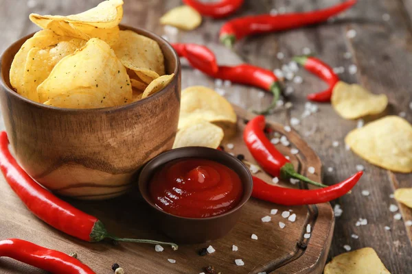 Schüssel mit knusprigen Kartoffelchips mit Chili und Soße auf Holztisch, Nahaufnahme — Stockfoto