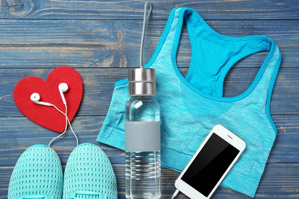 Gym ting, telefon og rødt hjerte på træ baggrund. Cardio træningskoncept - Stock-foto