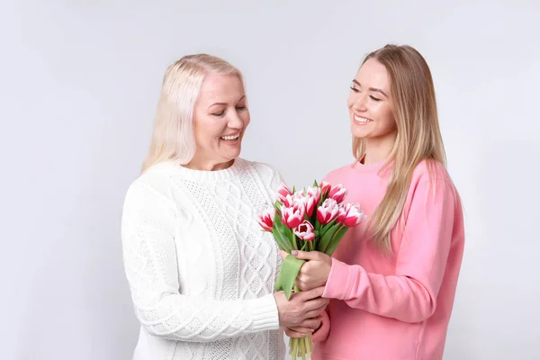 若い娘と明るい背景に花の花束を持つ母 — ストック写真