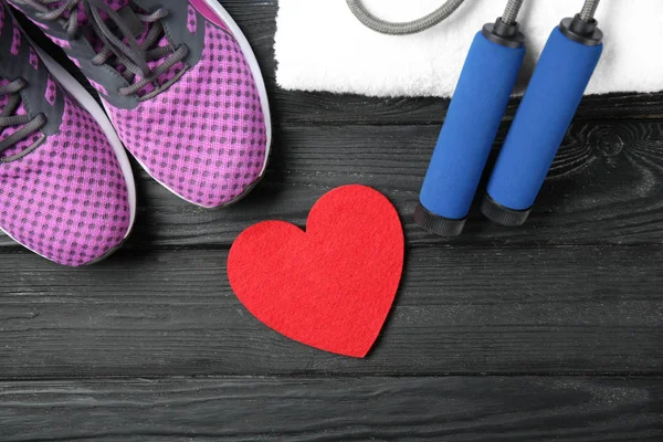 Palestra roba e cuore rosso su sfondo di legno. Concetto di allenamento cardio — Foto Stock