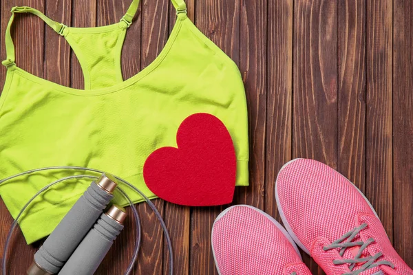 Palestra roba e cuore rosso su sfondo di legno. Concetto di allenamento cardio — Foto Stock