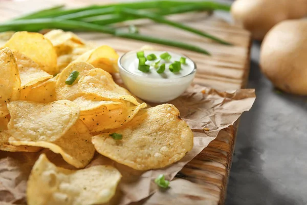 Patatas fritas crujientes con cebolla verde y crema agria en tablero de madera, primer plano — Foto de Stock