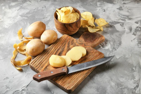 Composition with crispy chips and raw potato on grey table — Stock Photo, Image