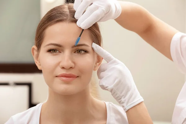 Young woman undergoing eyebrow correction procedure in salon — Stock Photo, Image