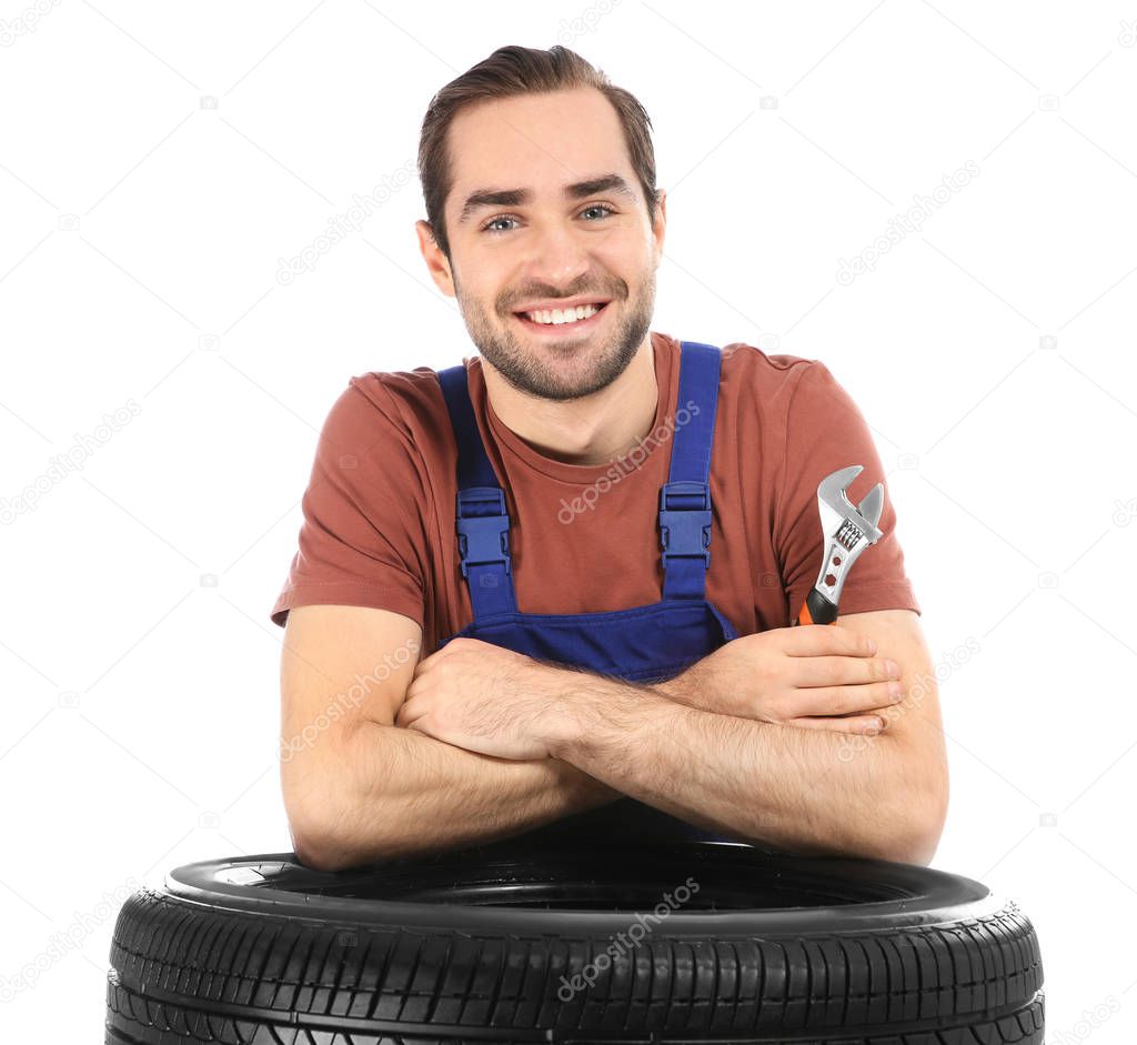 Young mechanic in uniform with car tire on white background