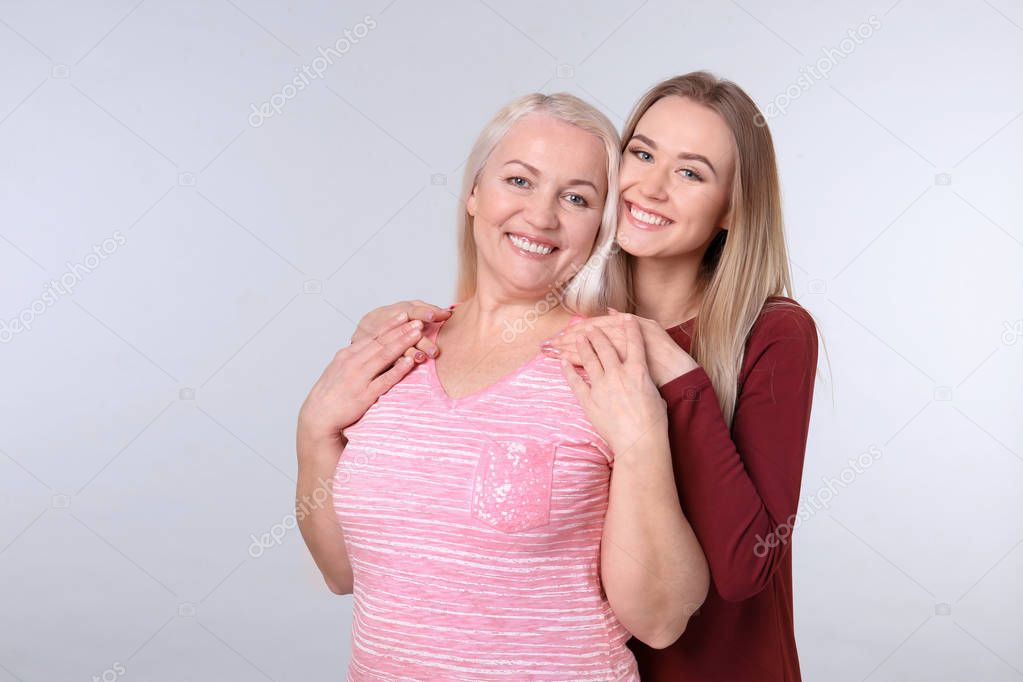 Young daughter and mother on color background