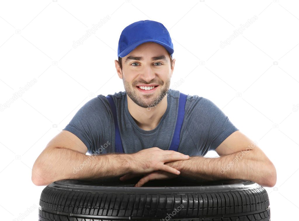 Young mechanic in uniform with car tire on white background