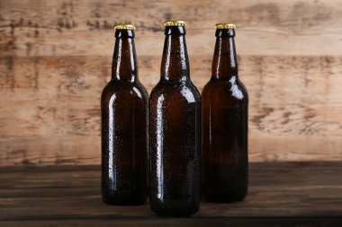 Ahşap arka planda cam şişelerde taze bira.