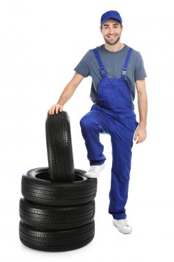 Beyaz arka plan üzerinde araba lastikleri ile üniformalı genç makinist