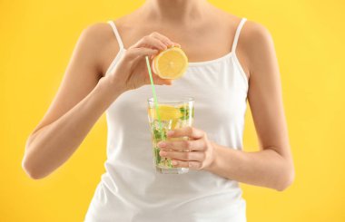 Genç kadın ile limonata renk arka plan üzerinde cam içine suyu sıkma