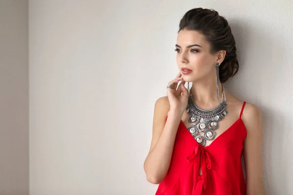 Mooie jonge vrouw met elegante sieraden op lichte achtergrond — Stockfoto