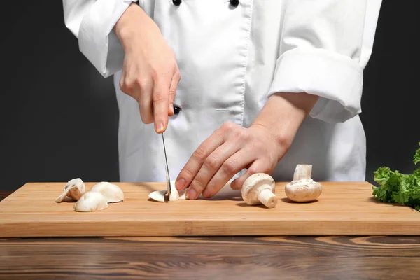 Female chef in uniform cutting mushrooms on board, closeup — Stock Photo, Image