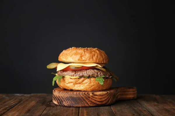 Leckere Burger auf Holzbrett vor dunklem Hintergrund — Stockfoto