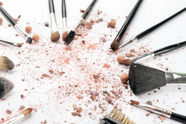 Make-up-Pinsel mit zerkleinerter Kosmetik des professionellen Künstlers auf weißem Hintergrund — Stockfoto