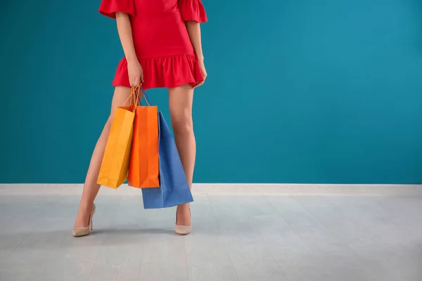 Bella giovane donna con borse della spesa contro parete a colori — Foto Stock