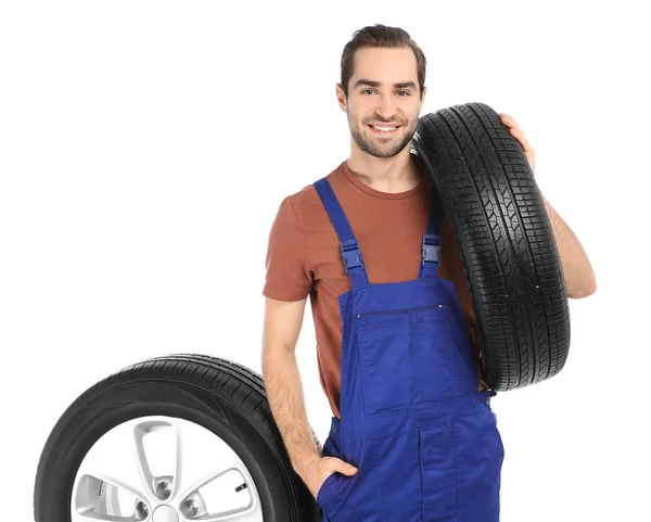 Young mechanic in uniform with car tires on white background — Stock Photo, Image