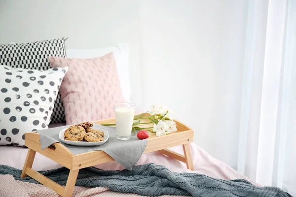 Vassoio con gustosa colazione e fiori sul letto — Foto Stock
