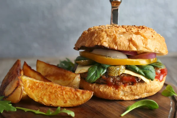 Sabrosa hamburguesa y patatas sobre tabla de madera —  Fotos de Stock