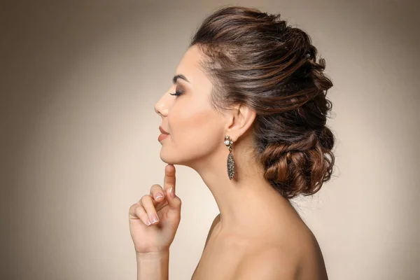 Krásná mladá žena s elegantní šperky na barvu pozadí — Stock fotografie