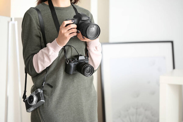 Young photographer with cameras, indoors