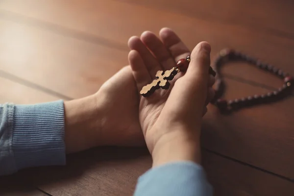 Menino segurando cruz de madeira à mesa — Fotografia de Stock