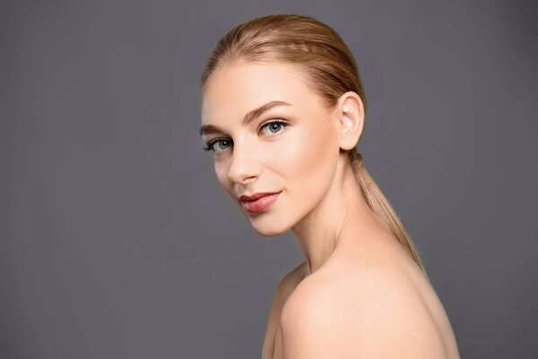 Portrait of beautiful young woman with clear skin on grey background