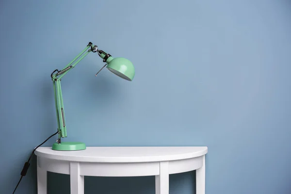 Elegante lámpara en la mesa cerca de la pared de color — Foto de Stock