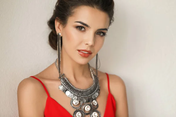 Hermosa mujer joven con joyas elegantes sobre fondo claro — Foto de Stock