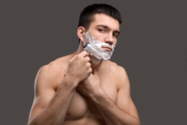 Yakışıklı genç adam tıraş oluyor.