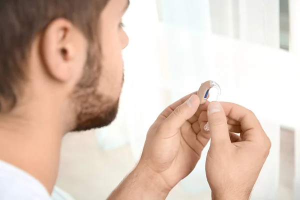 Giovane che tiene apparecchi acustici in casa — Foto Stock