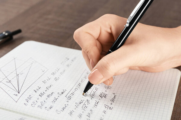 Woman doing homework in exercise book, closeup