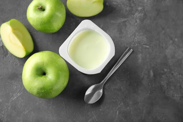 Plastikowy kubek z pyszne jabłko jogurt na tabeli — Zdjęcie stockowe