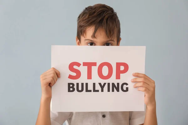 Niño pequeño sosteniendo el cartel con las palabras "Stop Bullying" sobre fondo gris —  Fotos de Stock