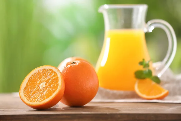 Oranges and pitcher with juice — Stock Photo, Image