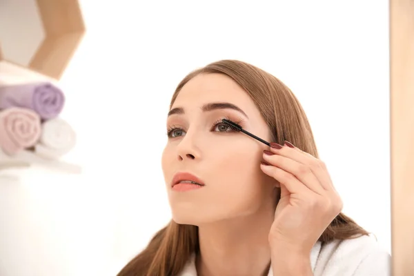 Ung kvinna applicera mascara på hennes ögonfransar inomhus — Stockfoto