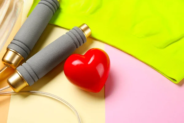 Roba da palestra e cuore rosso su sfondo a colori. Concetto di allenamento cardio — Foto Stock