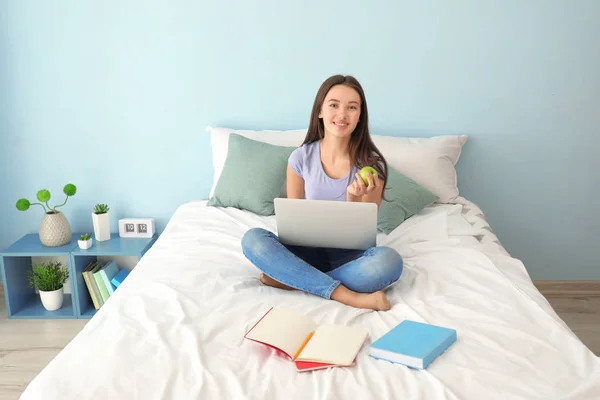 Милая девочка-подросток с ноутбука во время выполнения домашней работы в спальне — стоковое фото