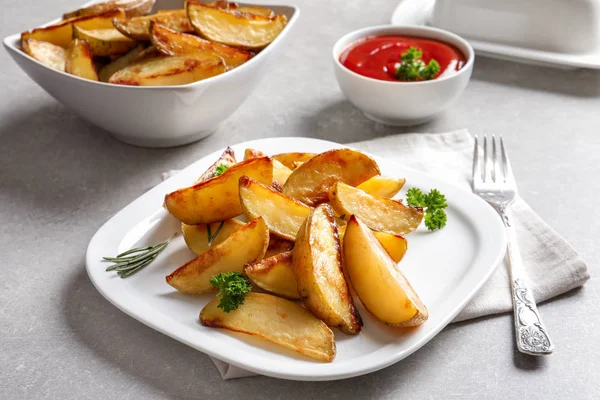 Prato com deliciosas fatias de batata assadas na mesa — Fotografia de Stock