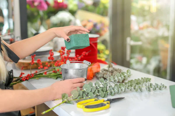 Женщина-флористка использует губку для работы в цветочном магазине — стоковое фото