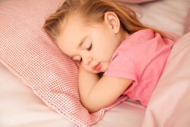 Evdeki yatakta uyuyan tatlı küçük kız.