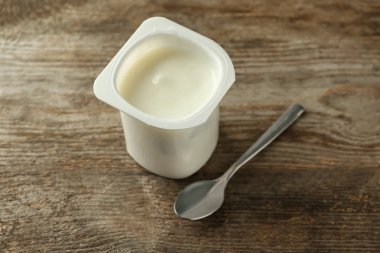 Ahşap masa üzerinde nefis vanilya yoğurt ile plastik bardak