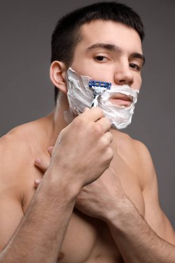 Yakışıklı genç adam tıraş oluyor.