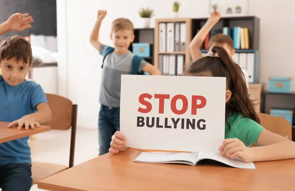 Kleines Mädchen mit Schild "Mobbing stoppen" im Klassenzimmer — Stockfoto