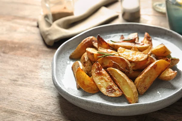 Plaat met smakelijke aardappel partjes op tafel — Stockfoto