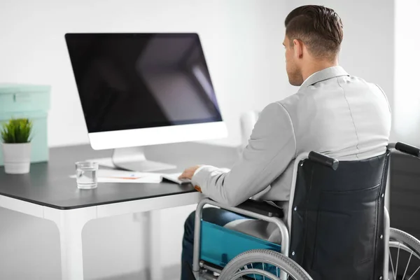 Młody człowiek na wózku inwalidzkim w miejscu pracy — Zdjęcie stockowe